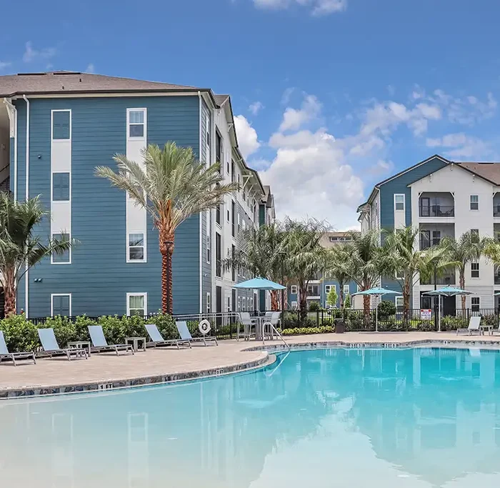 swimming pool and lounge deck in front of 4 story apartment buildings