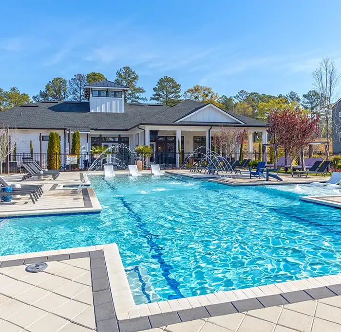 large swimming pool with a clubhouse building in the background