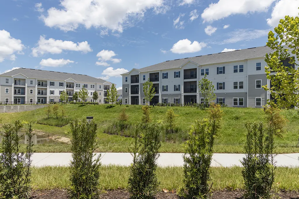 apartments buildings with a sidewalk and green shrub landscaping